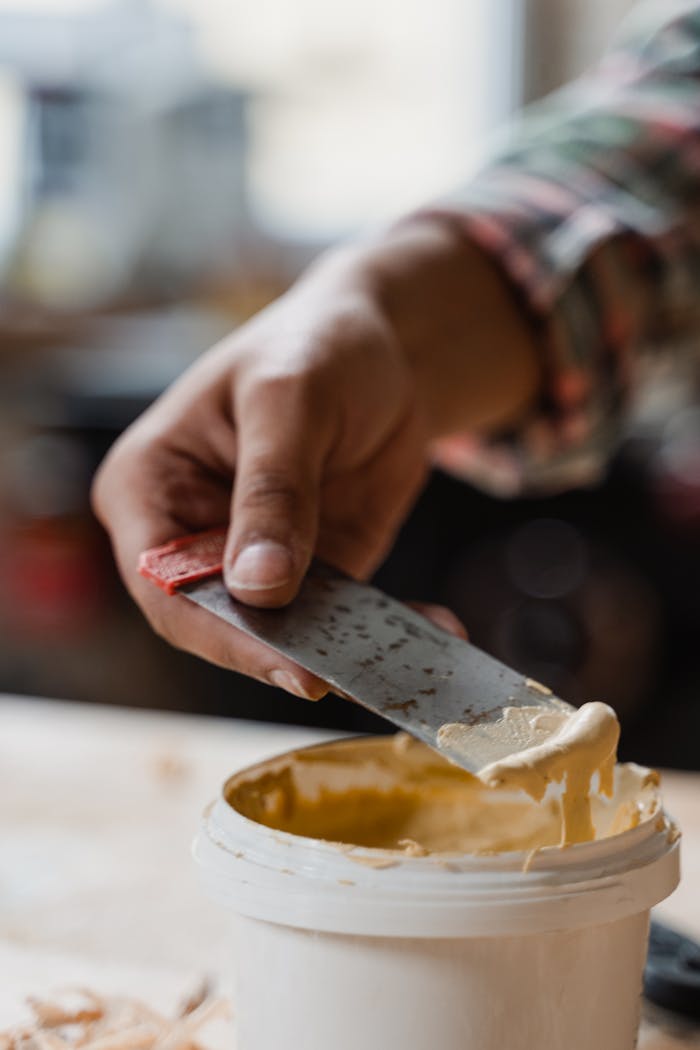 Focused image of a craftsman applying wood filler, showcasing artisanal skills and craftsmanship indoors.